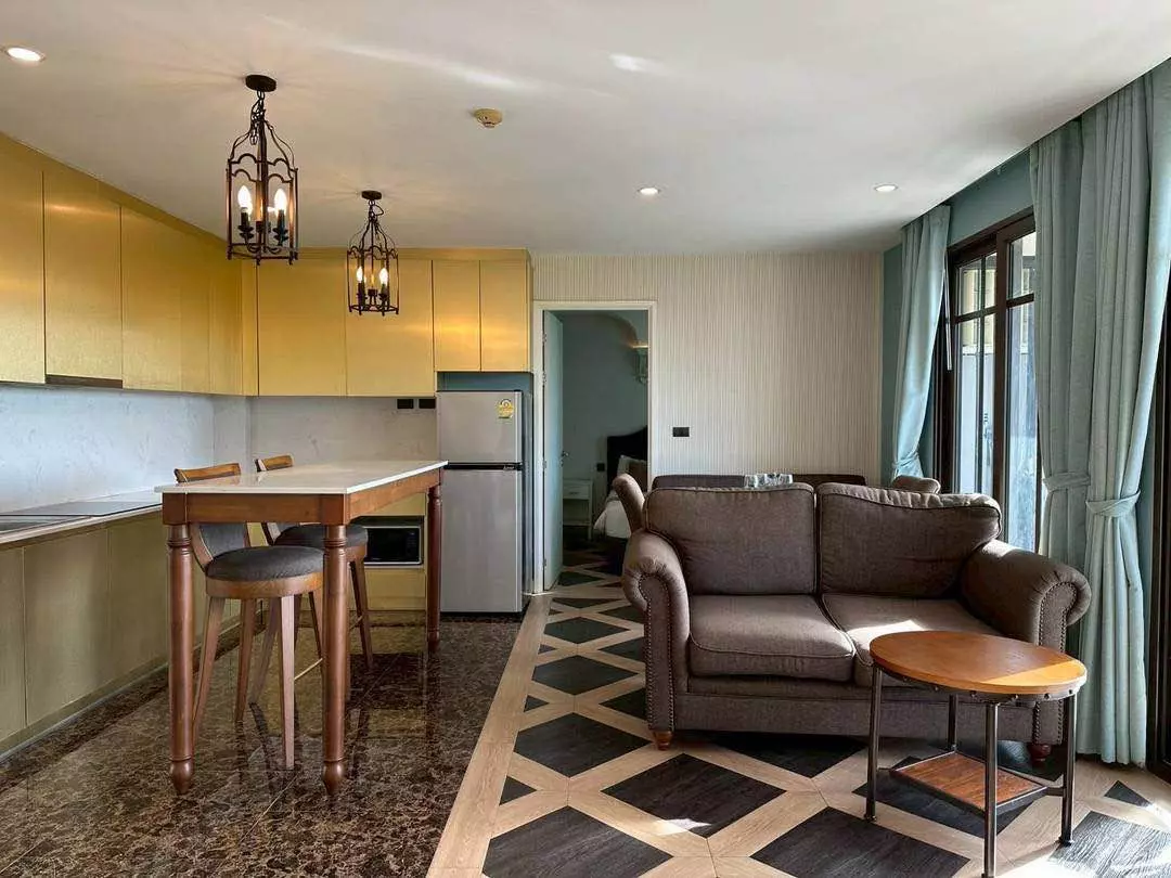 Open-plan living area with geometric tile floor and yellow kitchen cabinets in 2-bed condo for sale in Espana Condo Resort