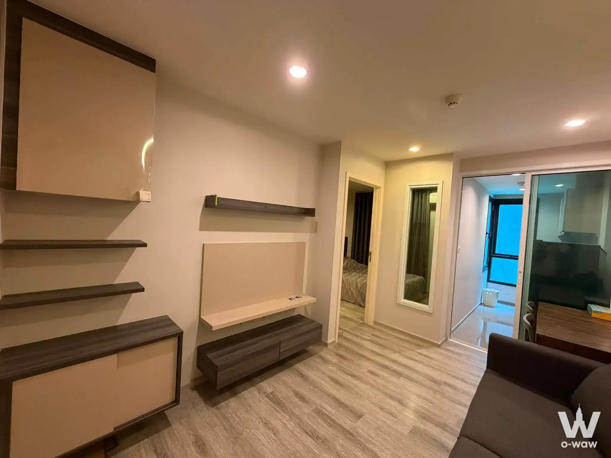 Living room in a Centric Ari Station condo with built-in walnut storage and sliding glass balcony door