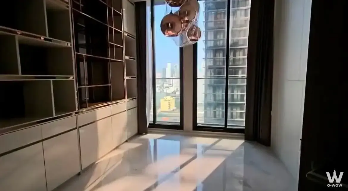 Unfurnished room in Noble Ploenchit condo featuring dark wood shelving, marble floors, and city view