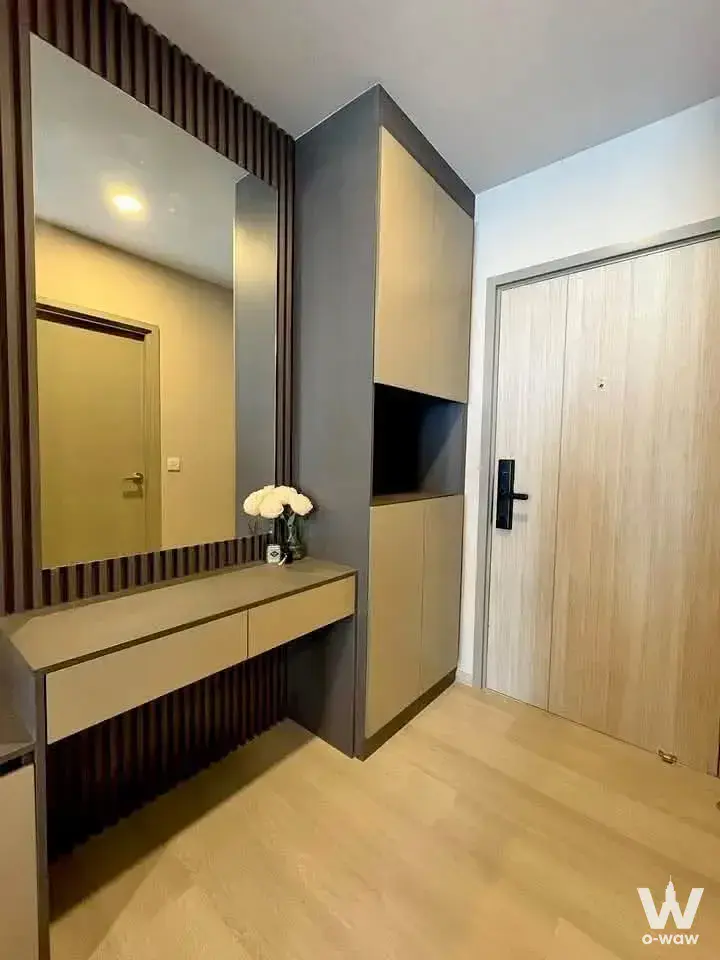 Modern 1-bed condo entryway at Aspire Onnut Station with light wood floors and dark slat paneling
