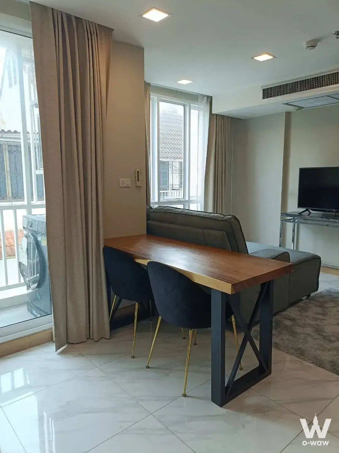 Living area in a 1-bed condo for rent at Bless Residence Ekkamai with walnut dining table and grey sectional sofa