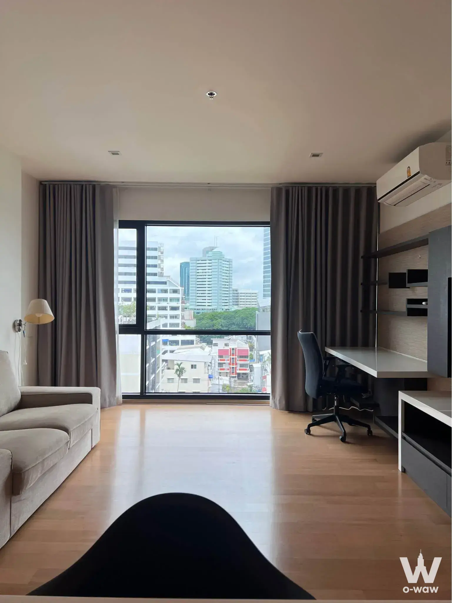 Modern condo living area featuring floor-to-ceiling windows with city views and built-in workspace in Noble Reflex