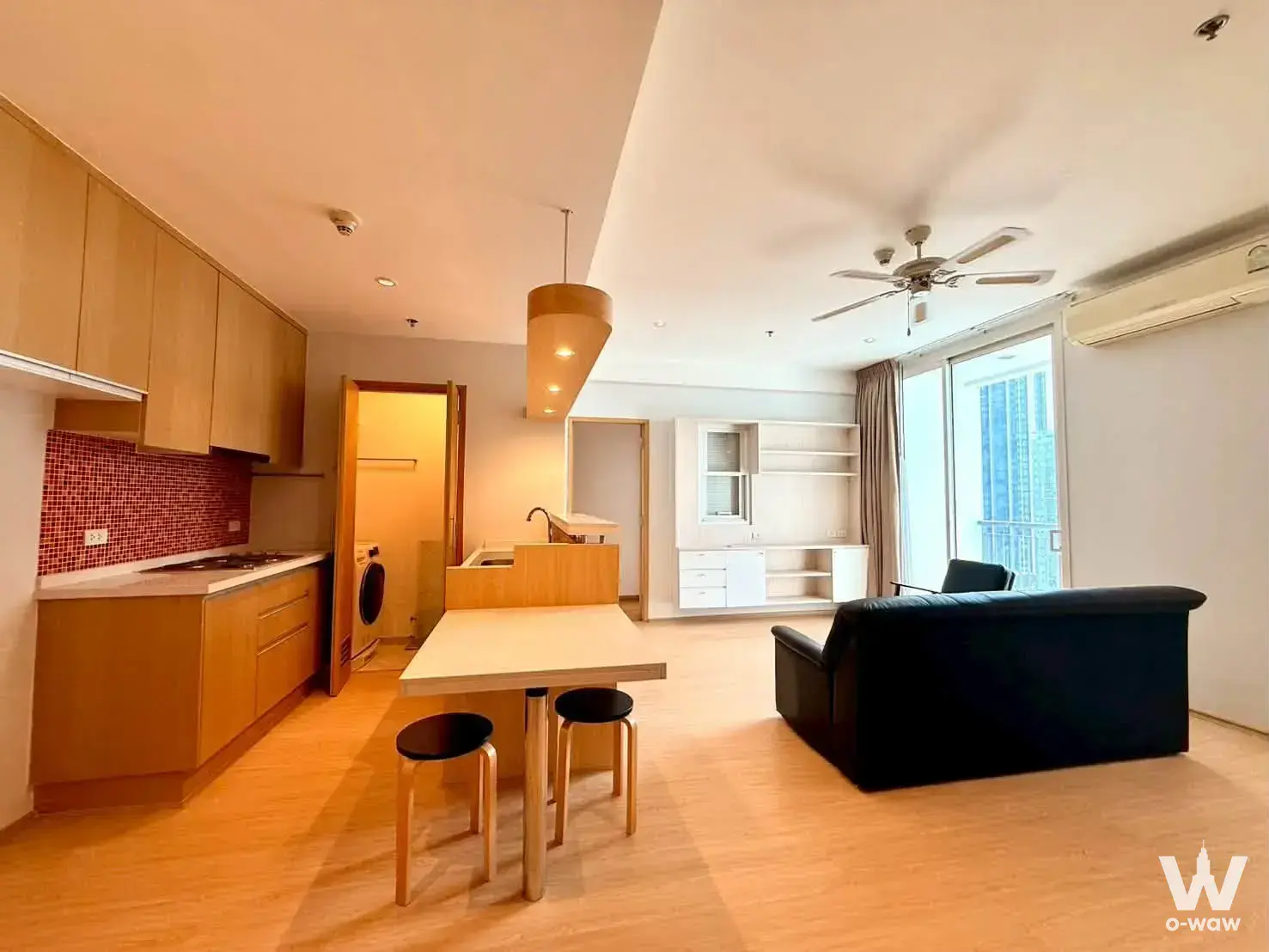 Open-plan living area in Villa Ratchatewi 2-bed house with red tile backsplash and black sofa