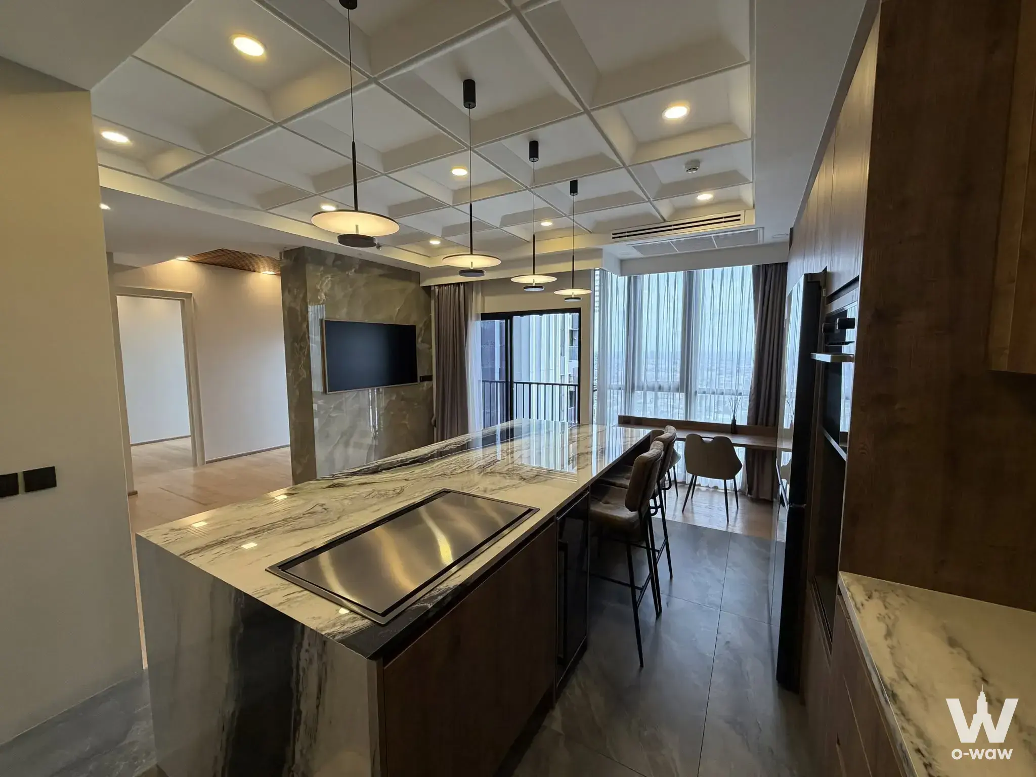 Open-plan kitchen in a Park Origin Thonglor condo with a marble island and dark wood cabinetry