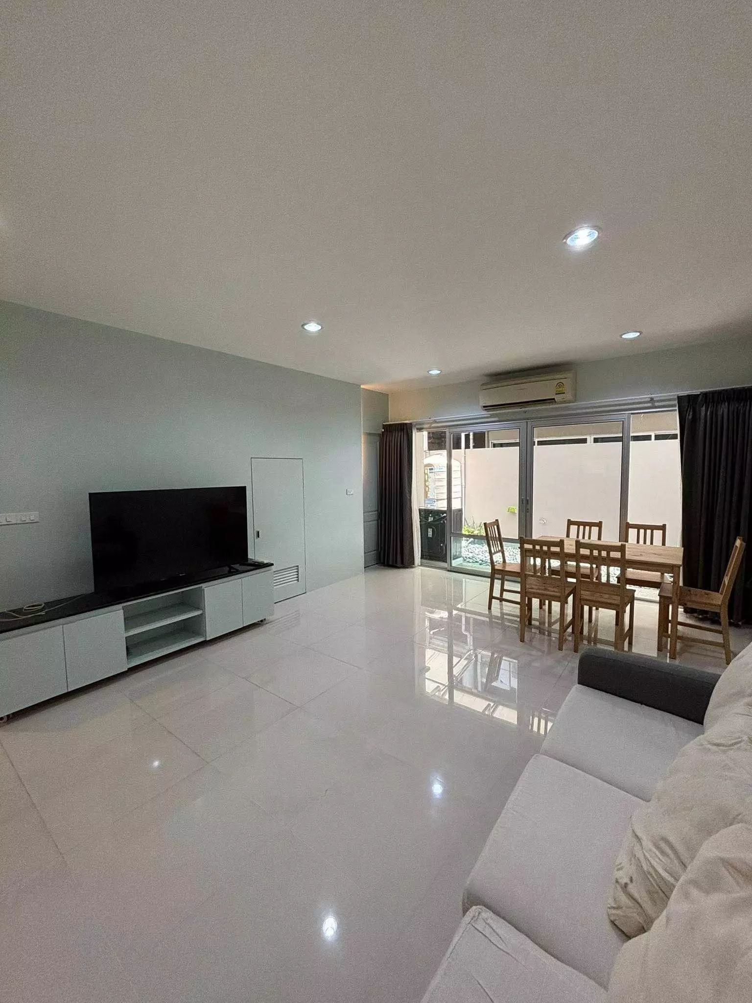 Open-plan living area with sage walls and wooden dining set in Noble Cube 2-bed condo