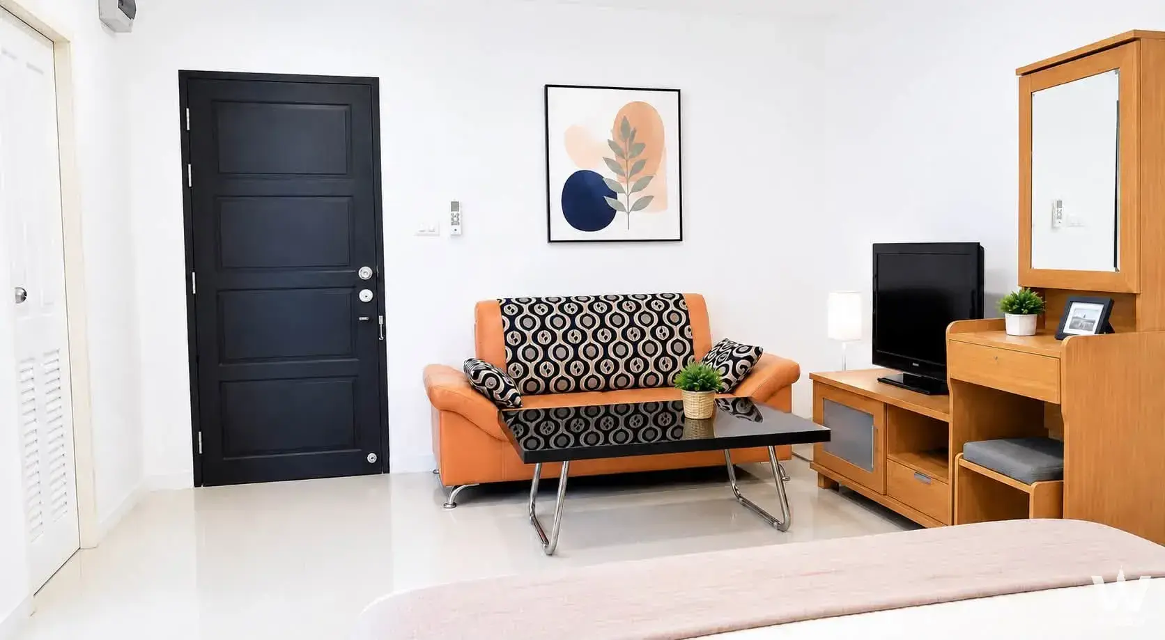1-bed condo for sale in The Breeze Condo featuring an orange leather sofa and geometric throw blanket