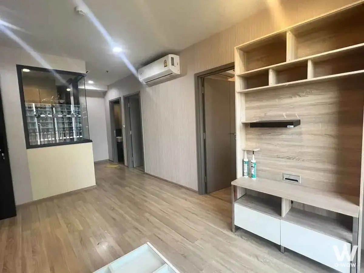 Unfurnished living area in THE BASE Garden Rama 9 featuring light oak floors and built-in wood shelving