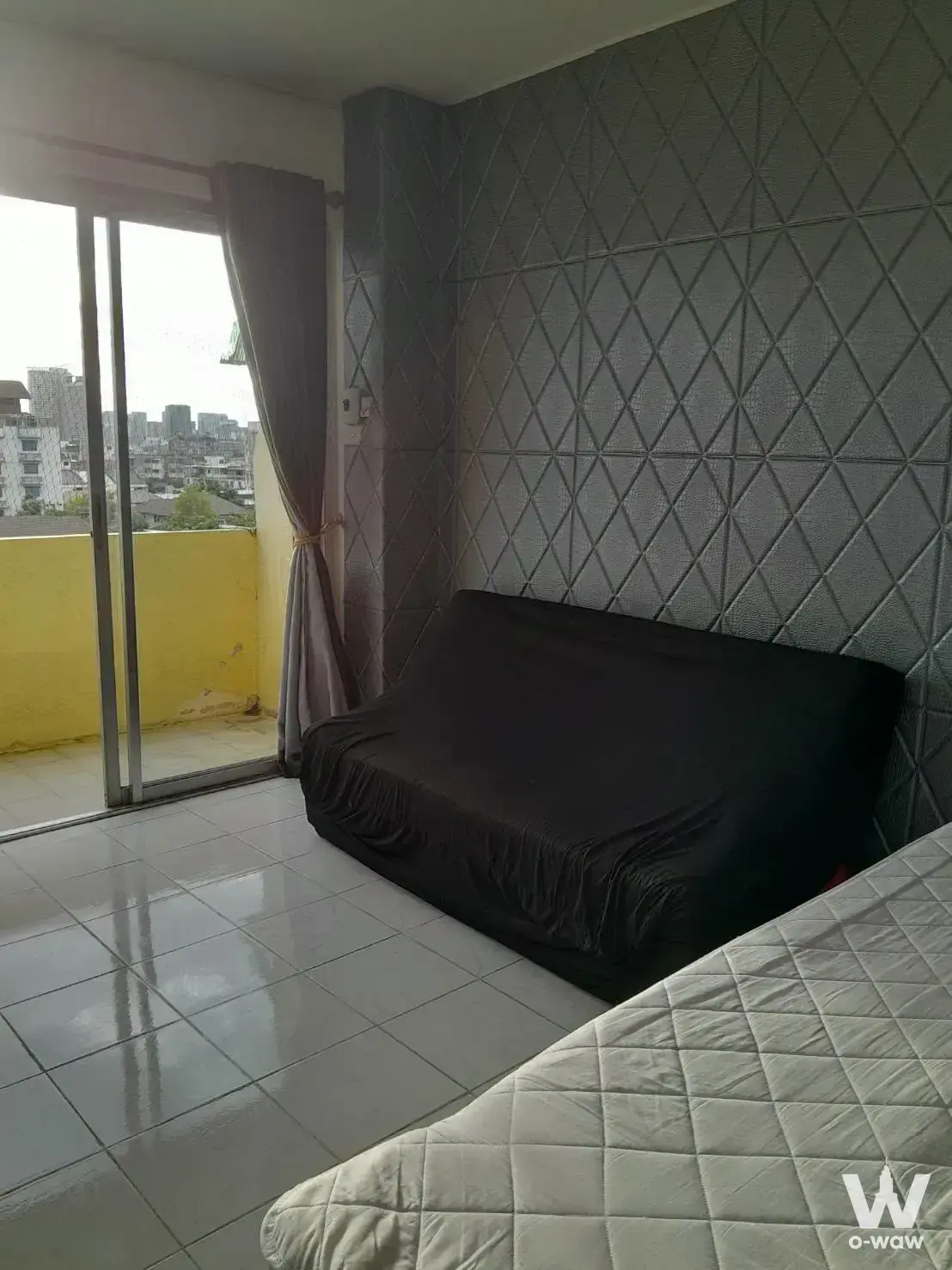 1-bed condo for rent in Family Park Condominium featuring grey padded feature wall, balcony with yellow parapet, and urban