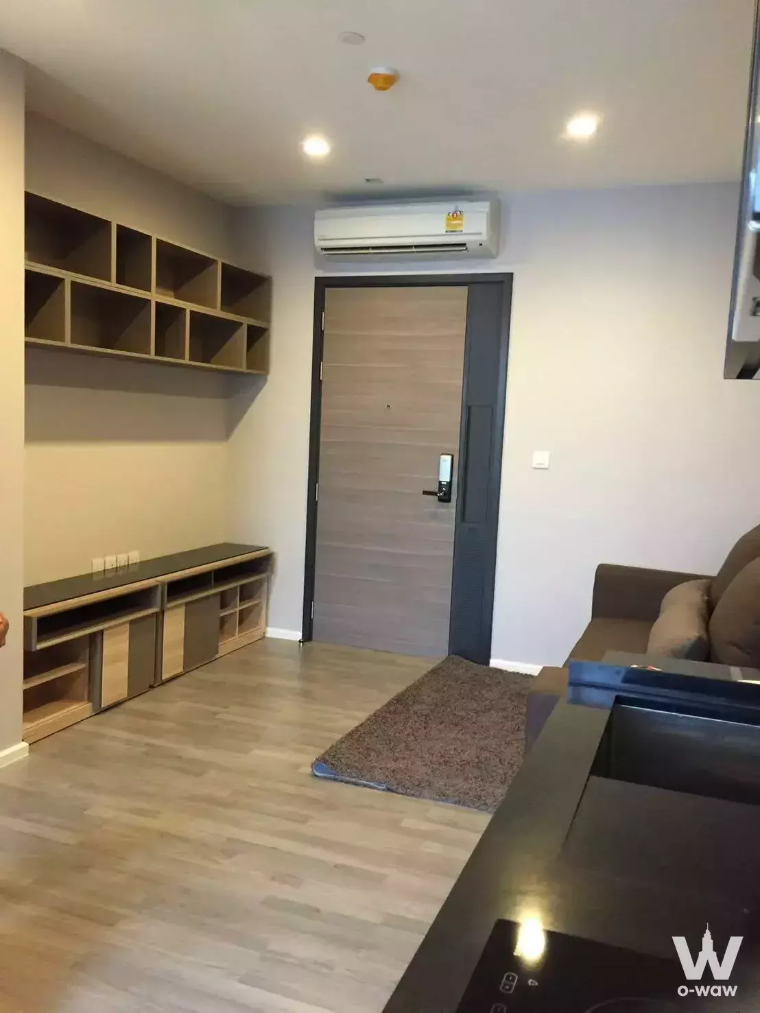 Unfurnished living room with wood flooring, built-in shelving, and smart lock door in The Room Sathon condo