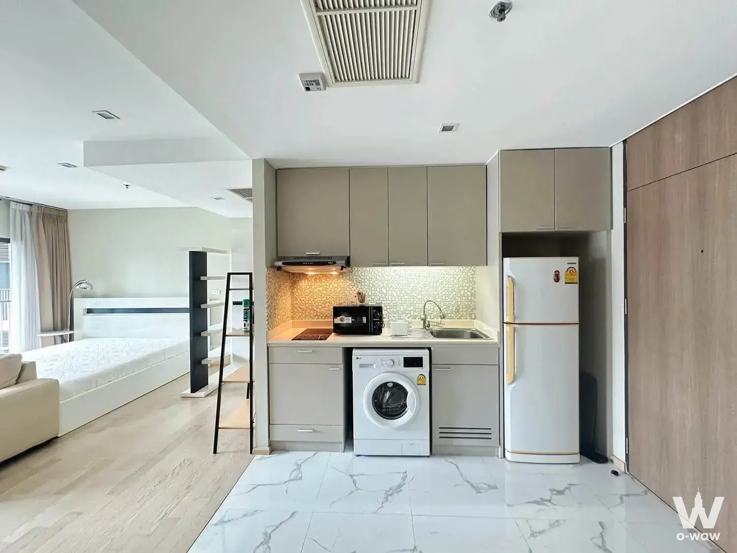 Studio kitchenette in Noble Remix with grey cabinets, induction cooktop, and adjacent platform bed area