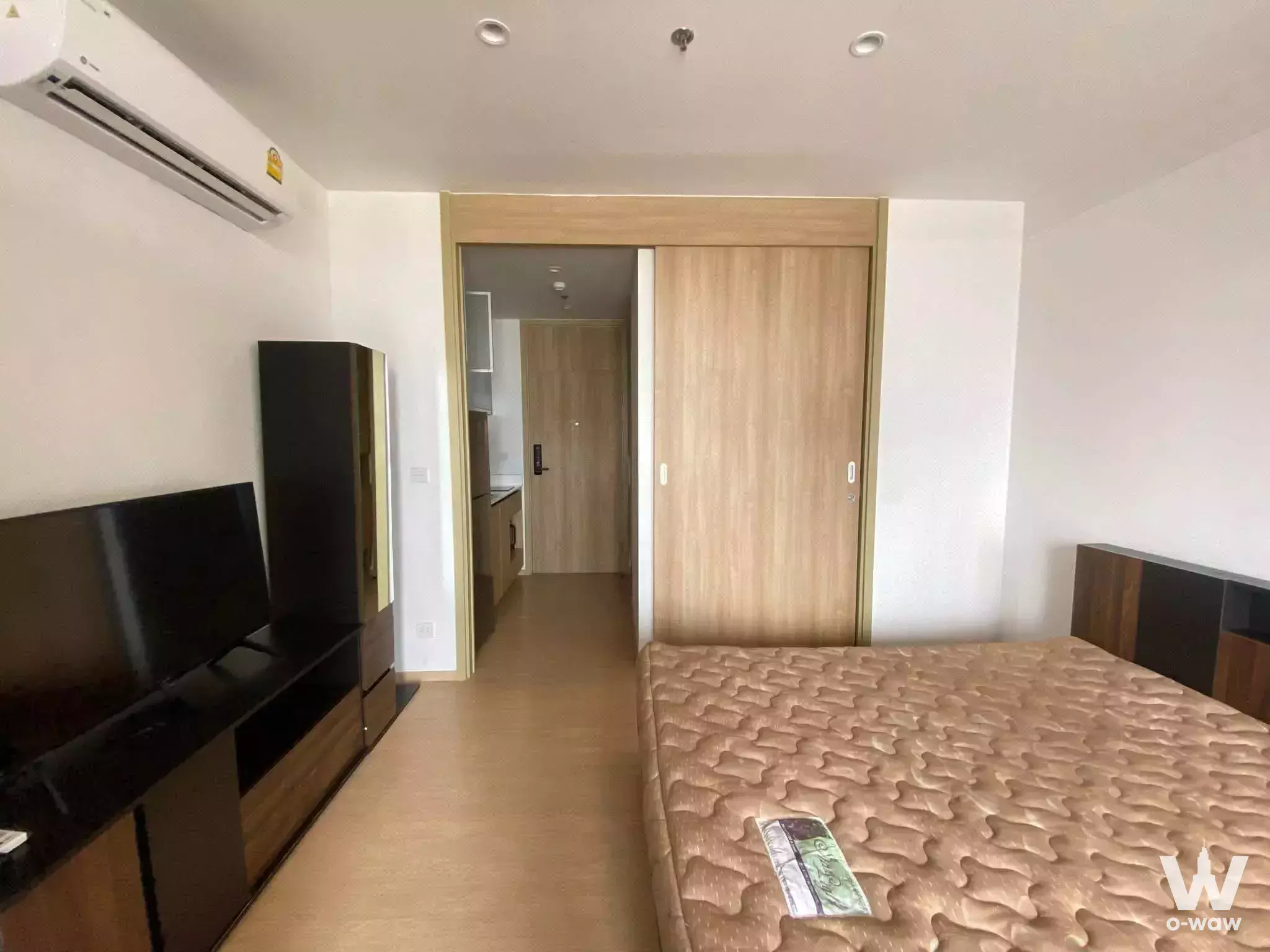 Unfurnished 1-bed bedroom at M Ladprao with dark wood wardrobe, TV console, and exposed mattress