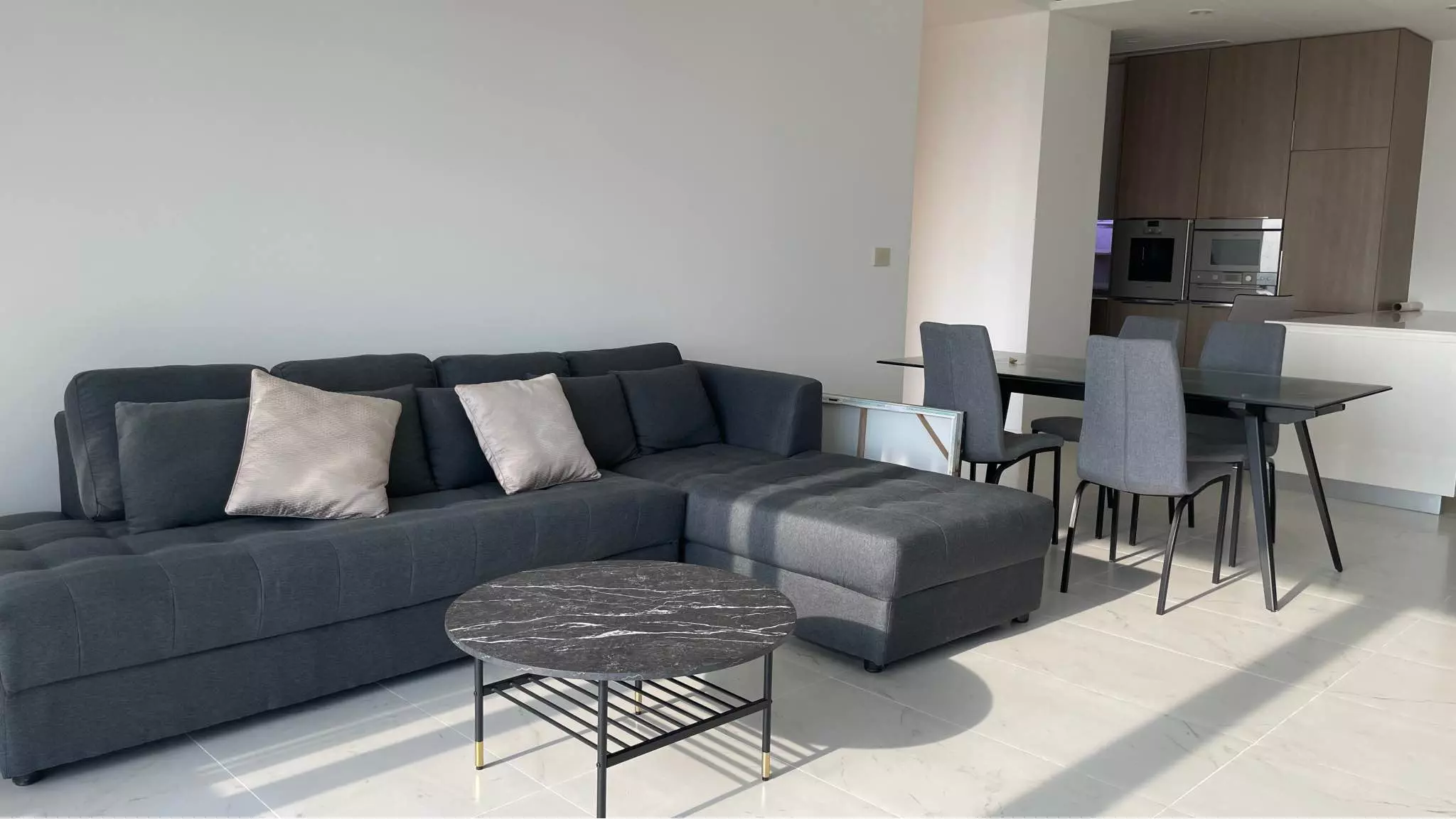 Open-plan living room in 185 Rajadamri 2-bed condo with grey sectional sofa and marble-effect floors