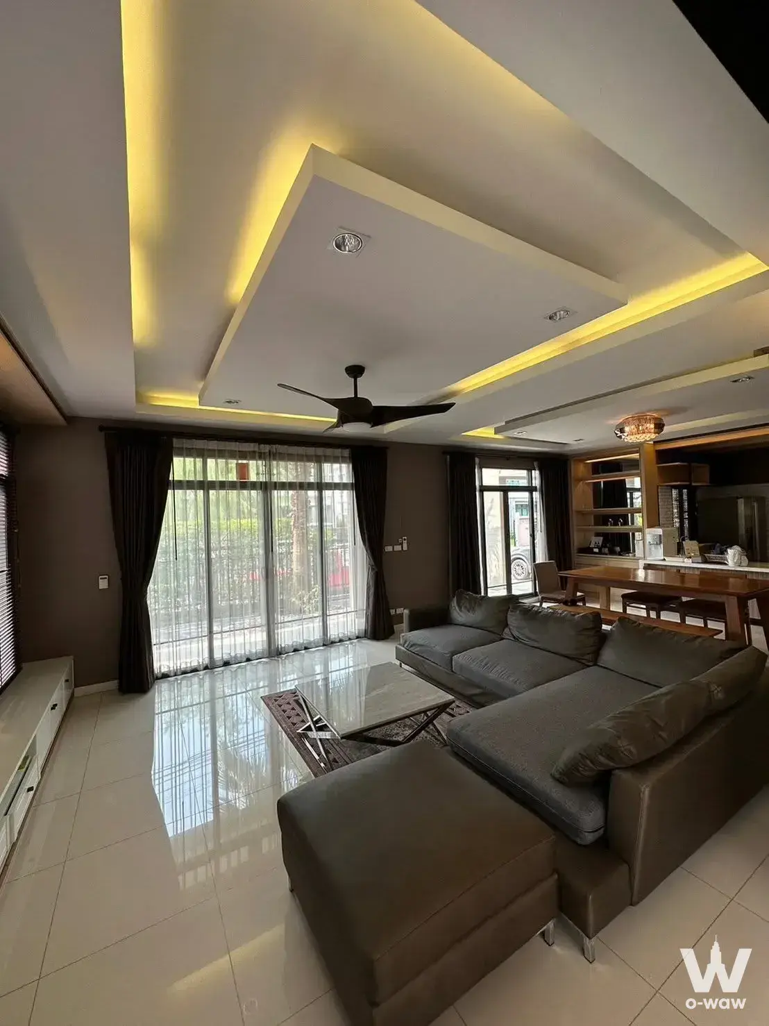 Spacious living area in 4-bed house for rent in The Palm Pattanakarn with grey sofa and dining zone
