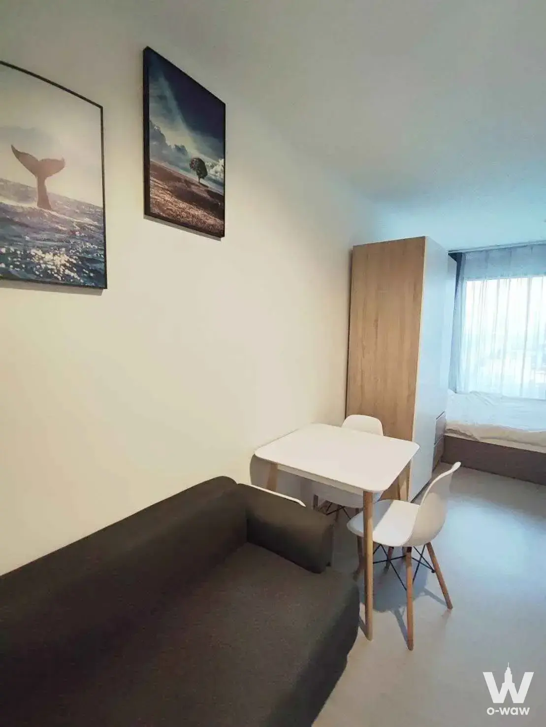 Compact 1-bed condo in Life Asoke Hype with grey sofa, white dining set, and light wood wardrobe