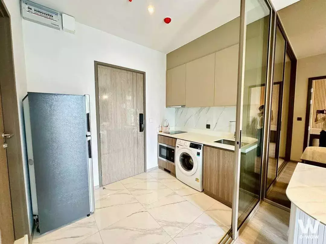 Kitchenette in Rhythm Ekkamai condo with marble tiles, smart lock door, and washing machine