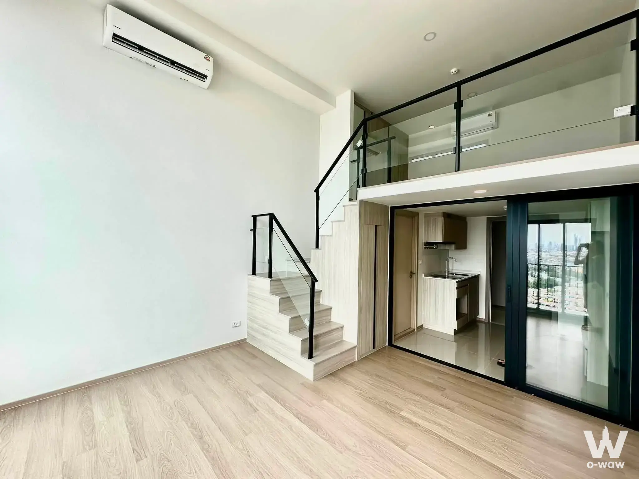 Empty loft studio in Origin Play Bangkhunnon featuring glass railing, mezzanine level, and city skyline view