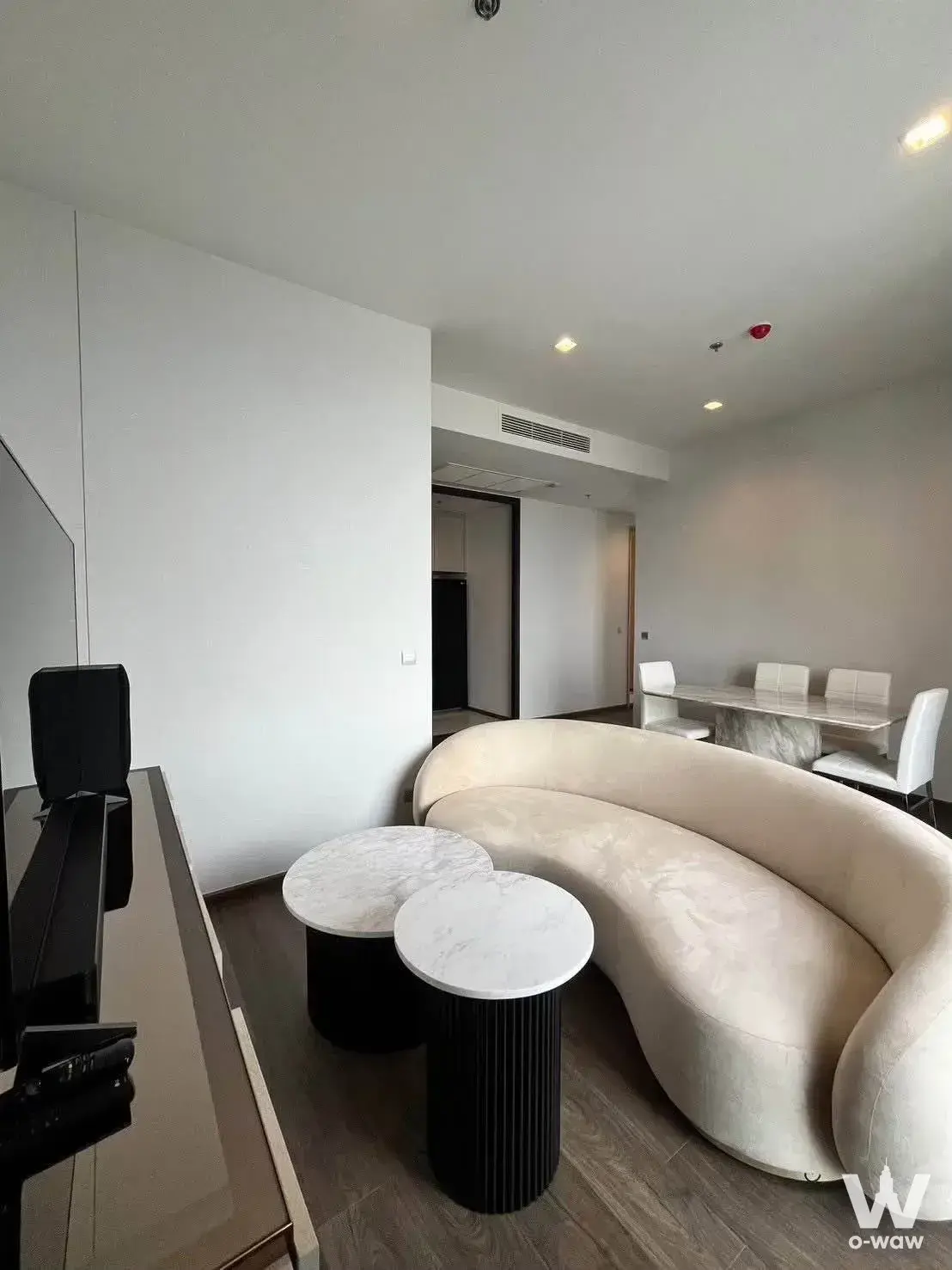 Curved cream sofa and marble coffee tables define the living room of this Siam-Ratchathewi rental