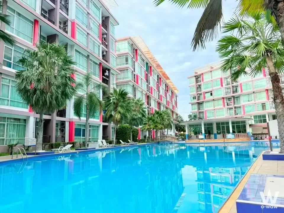 Resort-style pool at CC Condominium 1 with pink-accented buildings and palm trees