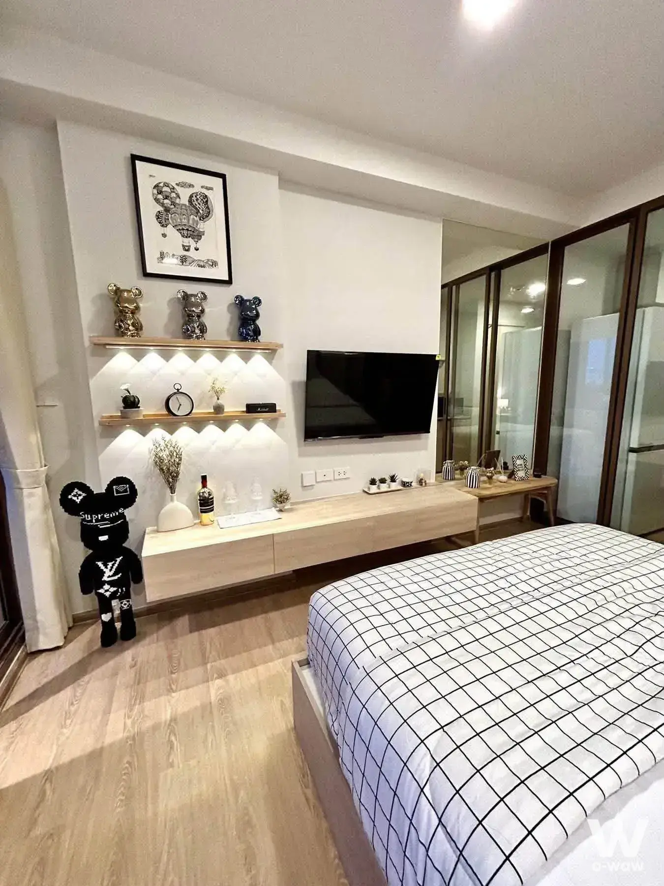 Modern bedroom with light oak floors, floating media console, and pop-culture decor in QUINTARA MHy'ZEN PHROM PHONG