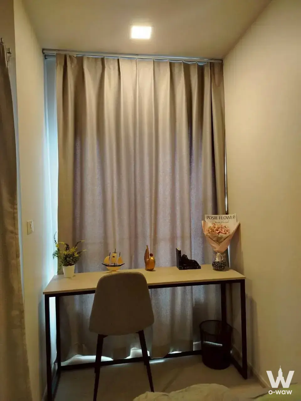 Bedroom study nook in FLO by Sansiri condo with large window, desk, and taupe curtains