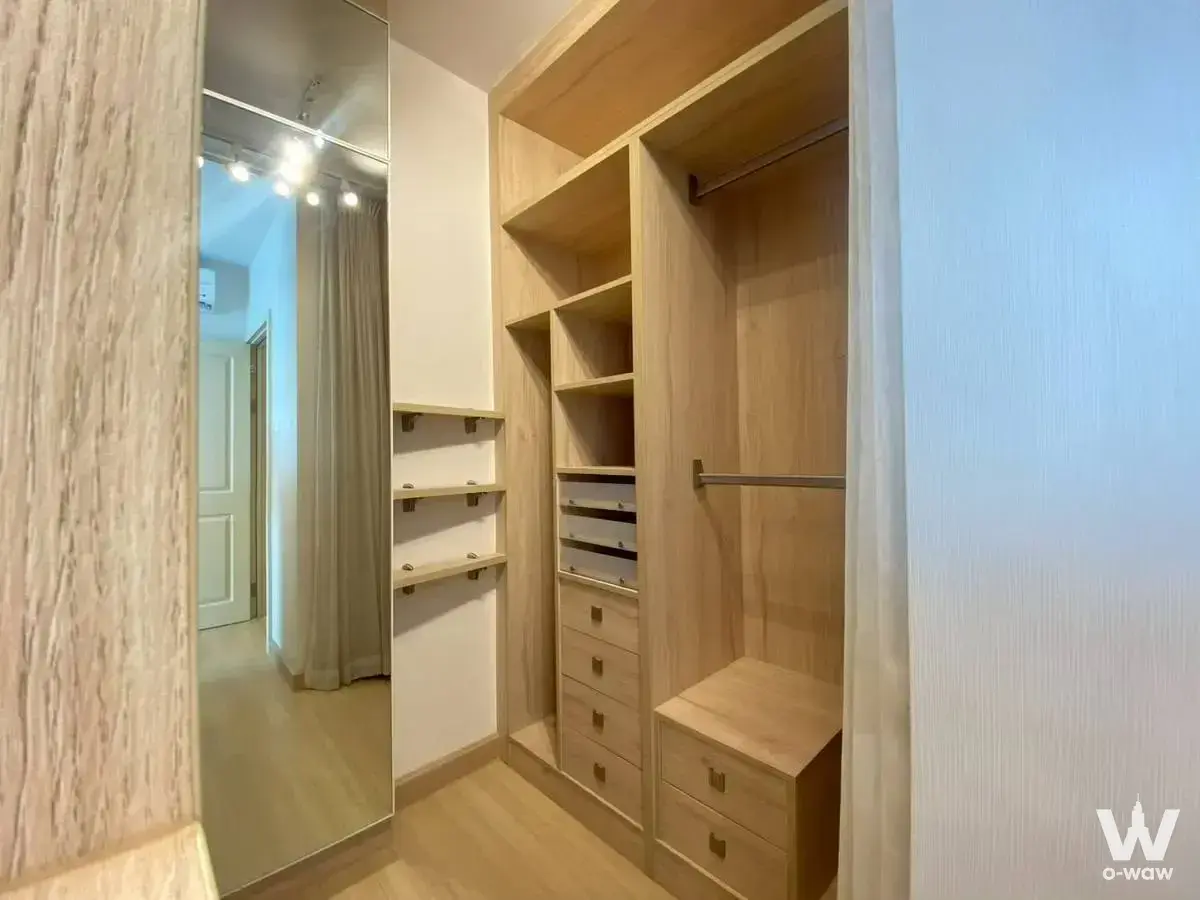 Spacious walk-in closet in Supalai Veranda Rama 9 condo featuring light wood cabinetry and mirror