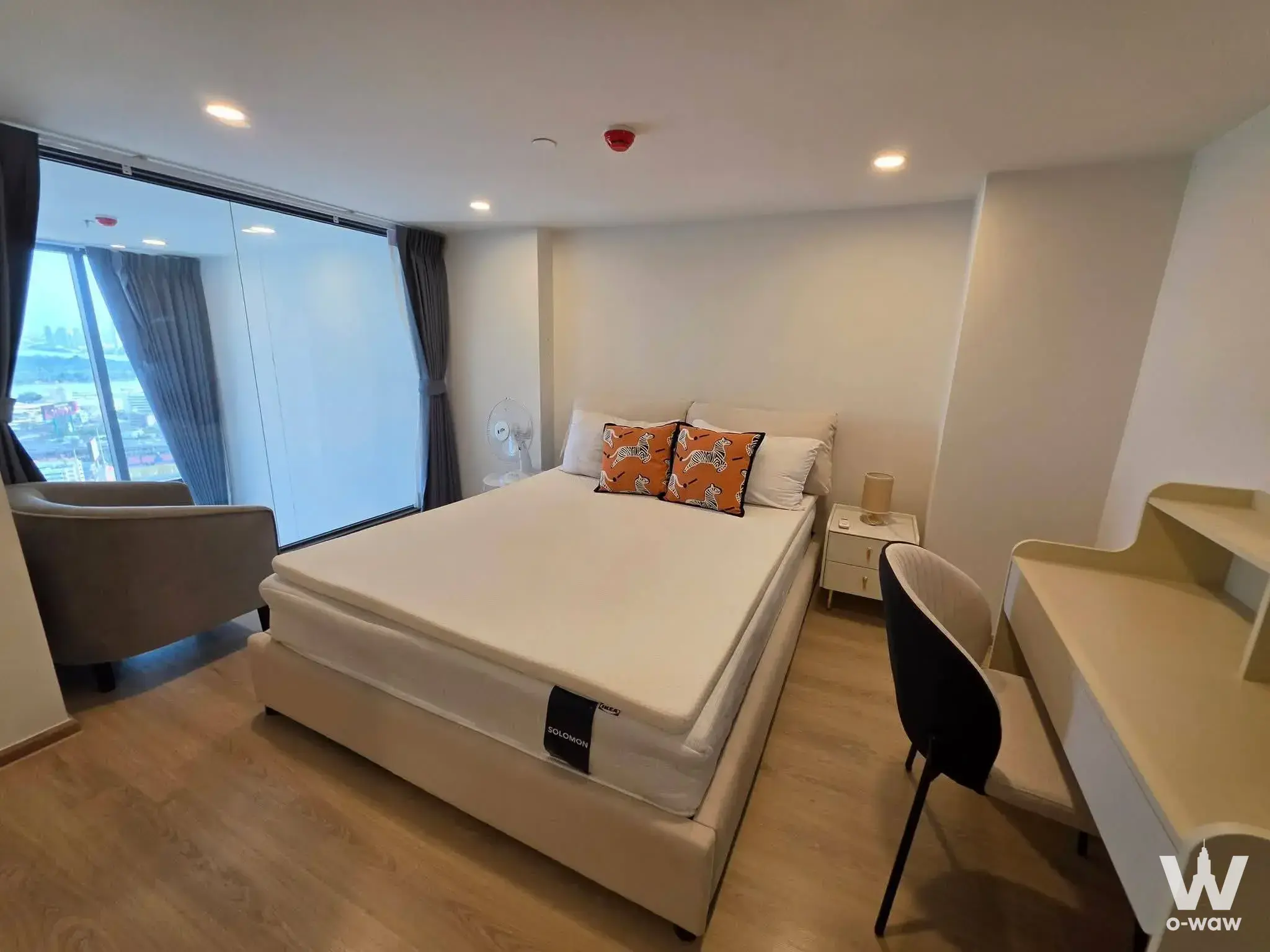 Life Rama 4 Asoke bedroom with orange zebra pillows, high-floor city view, and integrated workspace