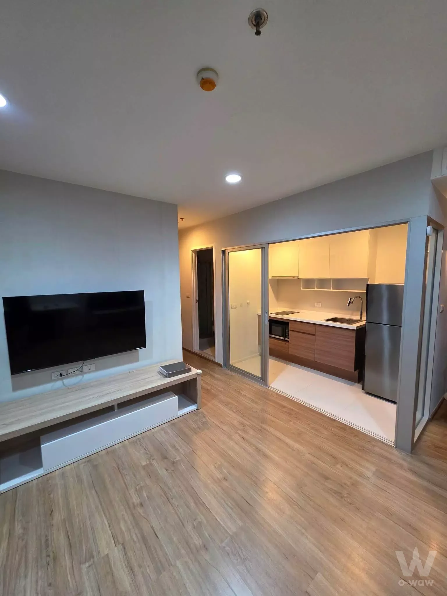 Unfurnished open-plan living room and kitchen with light wood floors in Fuse Chan Sathorn