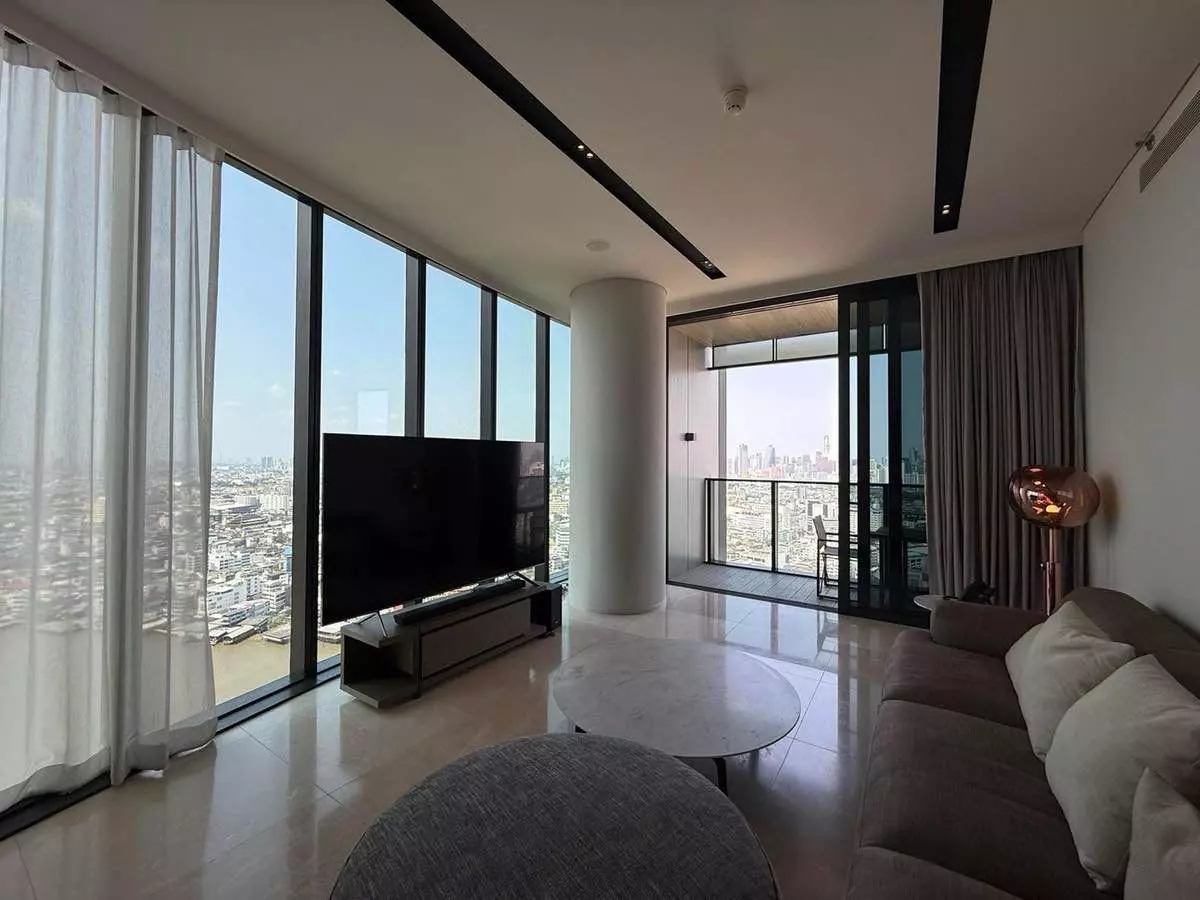 Living room with sectional sofa, marble table, and city river view in Banyan Tree Residences 2-bed condo