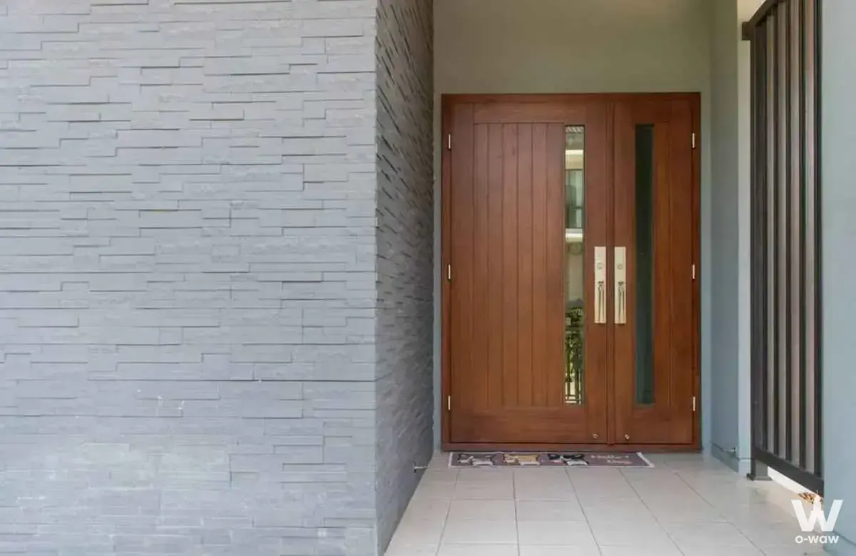 Wooden double door entrance with stacked stone wall at The City Ratchaphruek