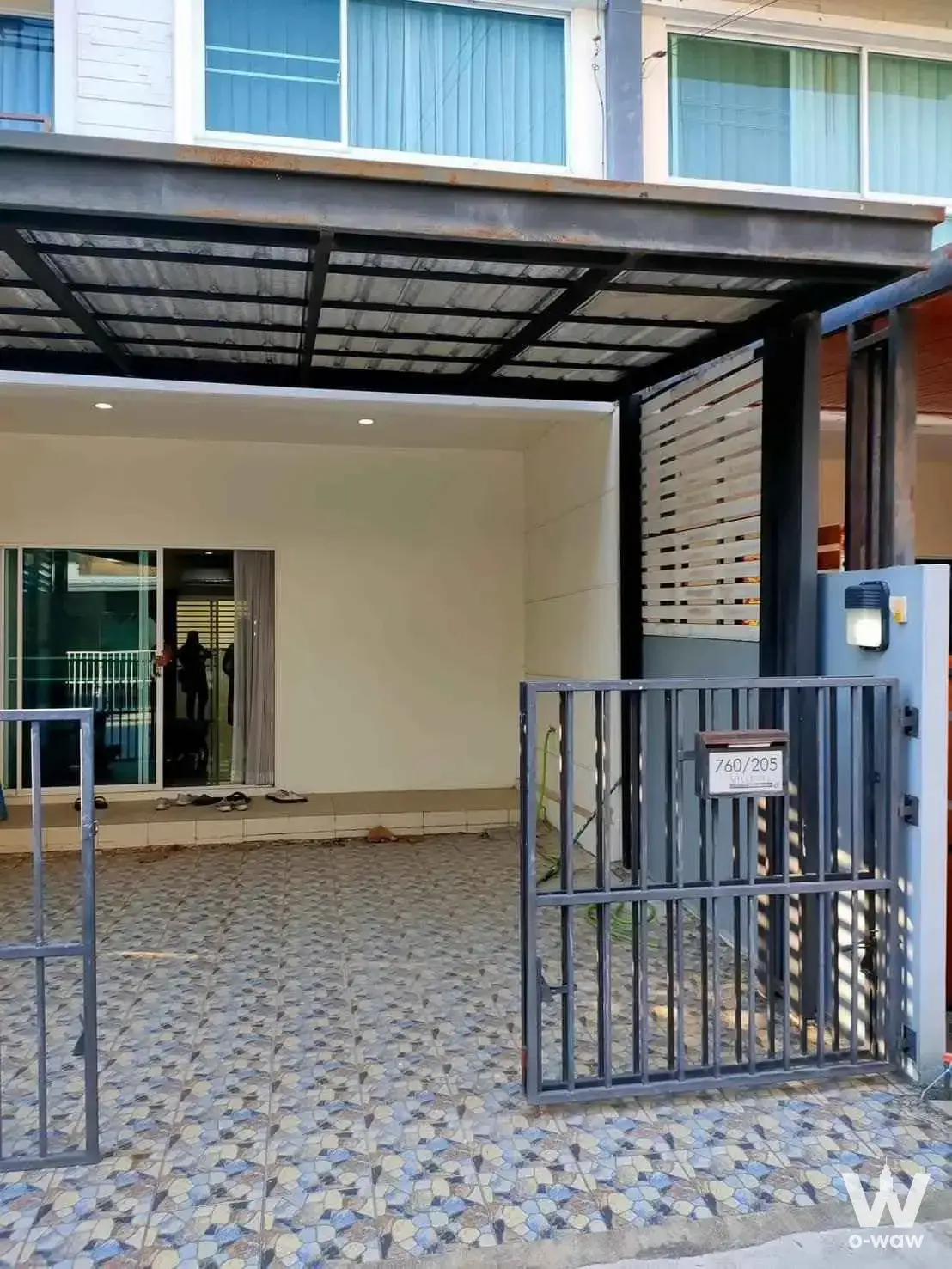 Exterior entrance of Villet City Pattanakarn townhouse featuring mosaic tile courtyard, black metal gate, and covered