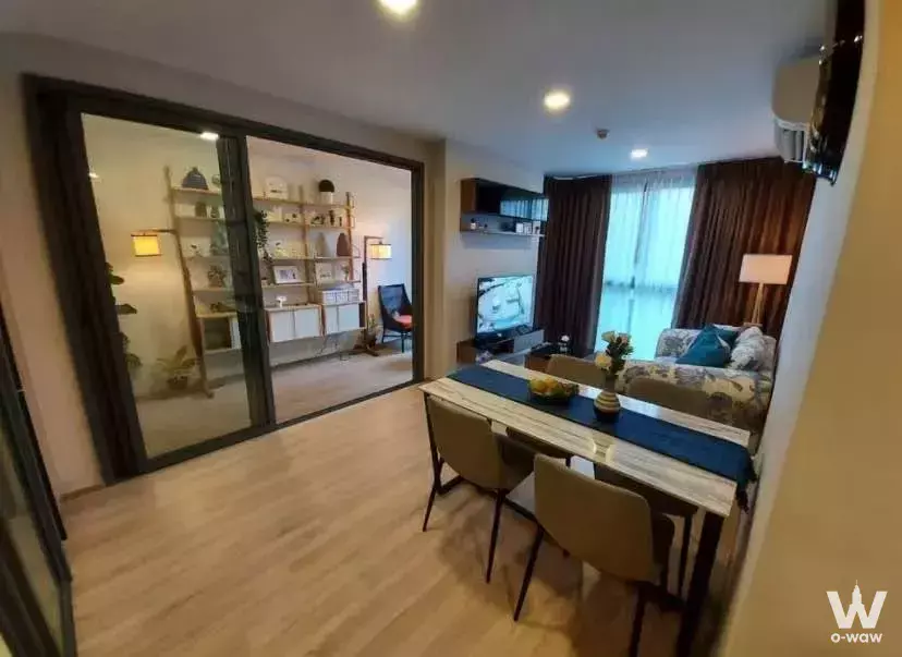 Living and dining area of 2-bed condo for rent in TAKA HAUS with distressed table, patterned sofa, and sheer curtains