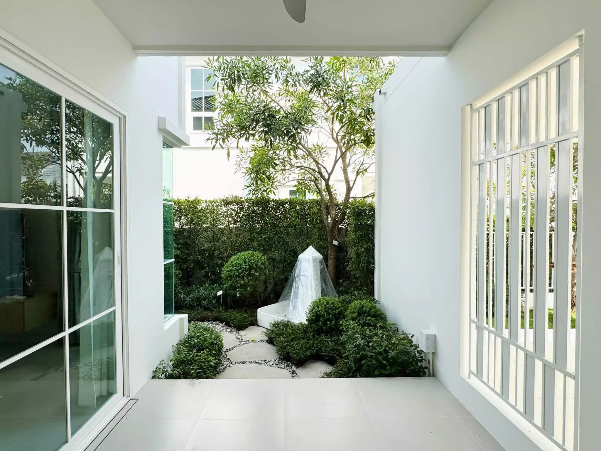 Covered patio opening to private garden courtyard at Chaiyapruek Bangna house