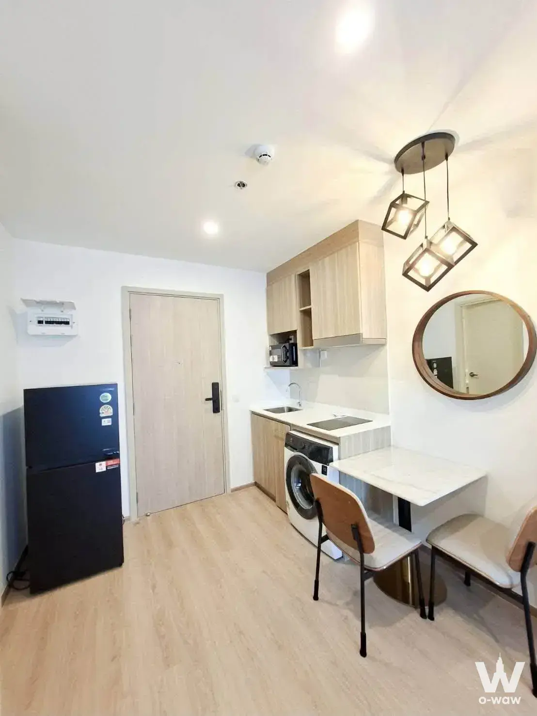 Compact 1-bed condo kitchen-dining nook in Life Rama 4 with light wood floors, white walls, and modern minimalist furnishings