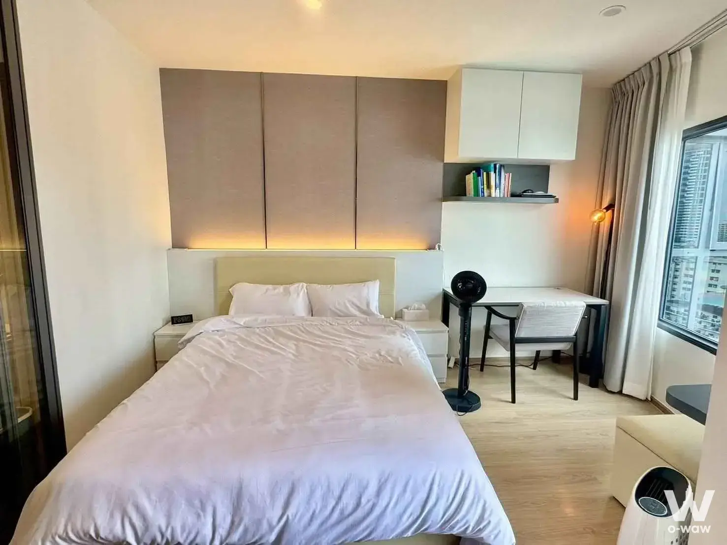 Bright bedroom in Life Rama 4 - Asoke with taupe padded headboard, LED lighting, and city high-rise views