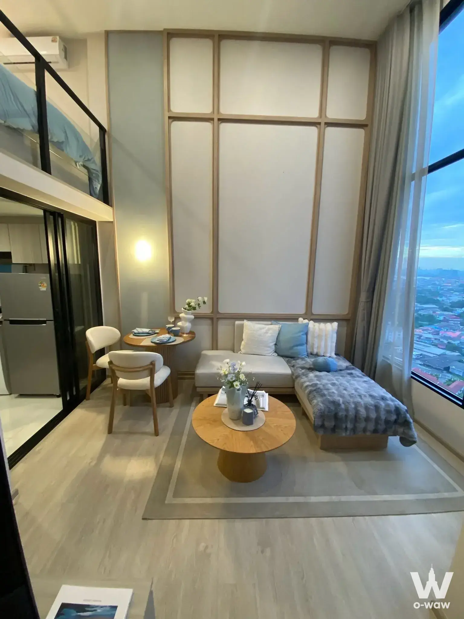 Loft-style studio in Origin Plug & Play E22 with mezzanine bed and city view at dusk