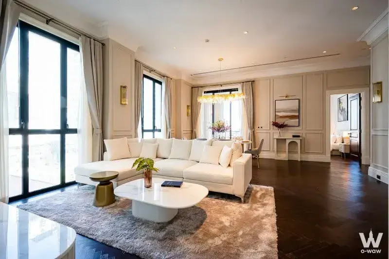 Cream paneled living room with herringbone floors and marble table in a 2-bed condo for sale at 98 Wireless