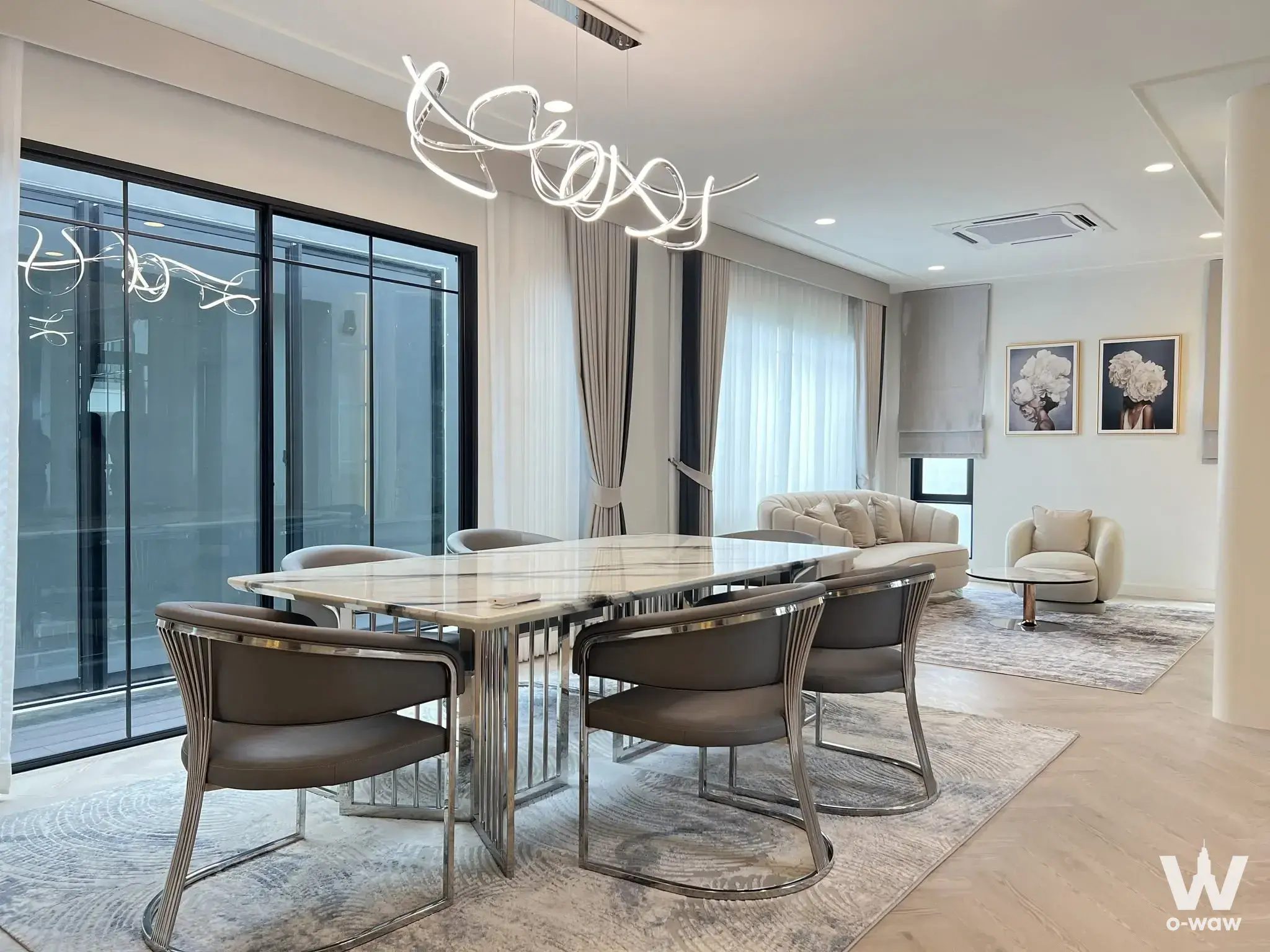 Bright dining area in a 4-bed Setthasiri house with marble table and sculptural chandelier