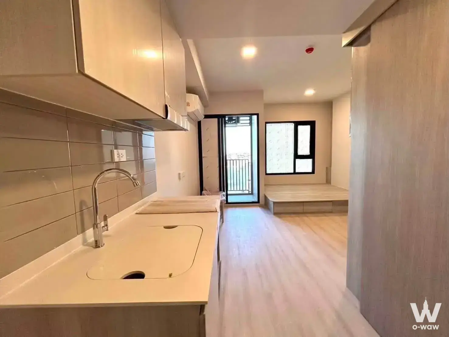 COBE Ratchada studio with white kitchenette, raised platform bed, and balcony access
