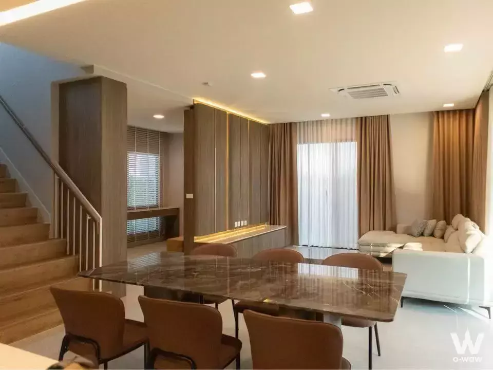 Spacious open-plan living area in Mantana Bangna house for rent, with marble dining table and wood accents