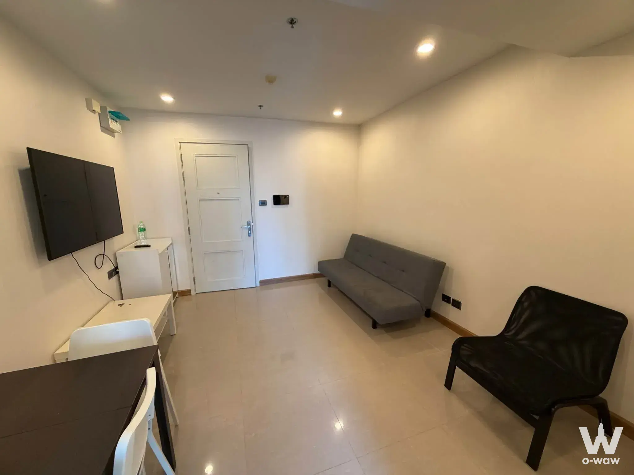 Sparsely furnished living room in a Supalai Wellington II condo with grey sofa and dark wood dining table