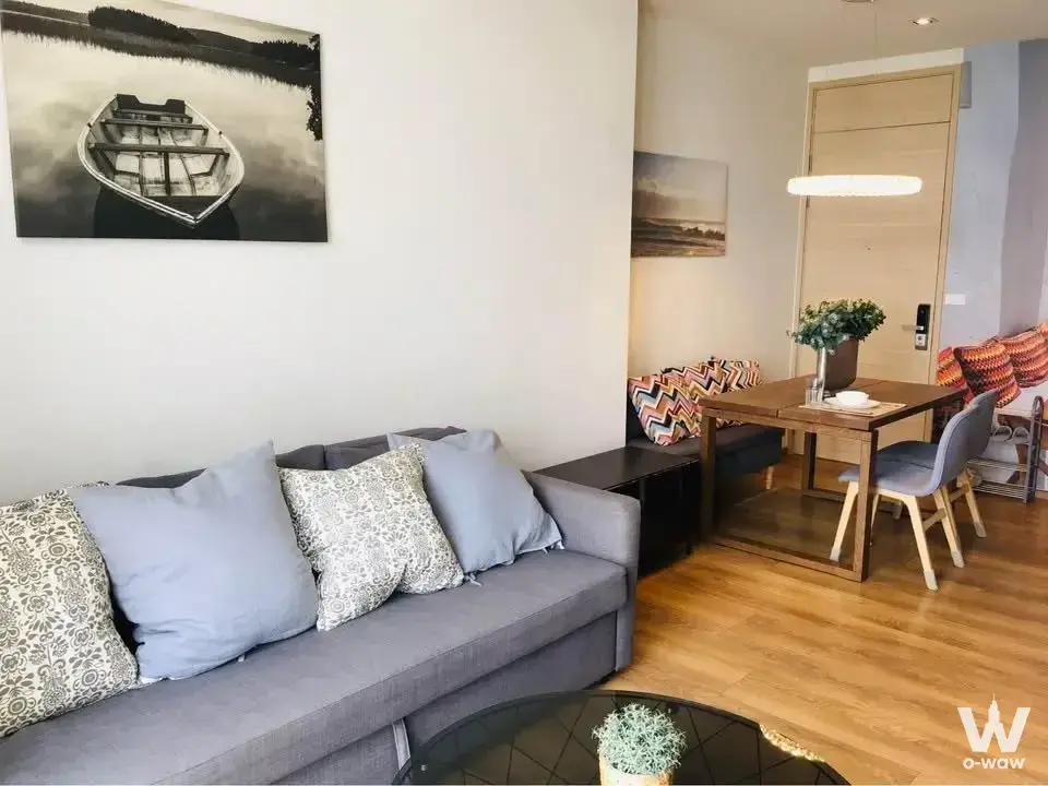 Furnished living room with blue pillows and art in a Park Origin Phrom Phong condo