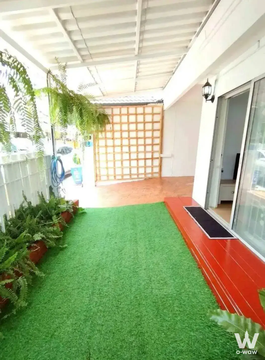Townhouse patio in Pruksa 49/2 featuring artificial turf, wooden deck, and hanging ferns