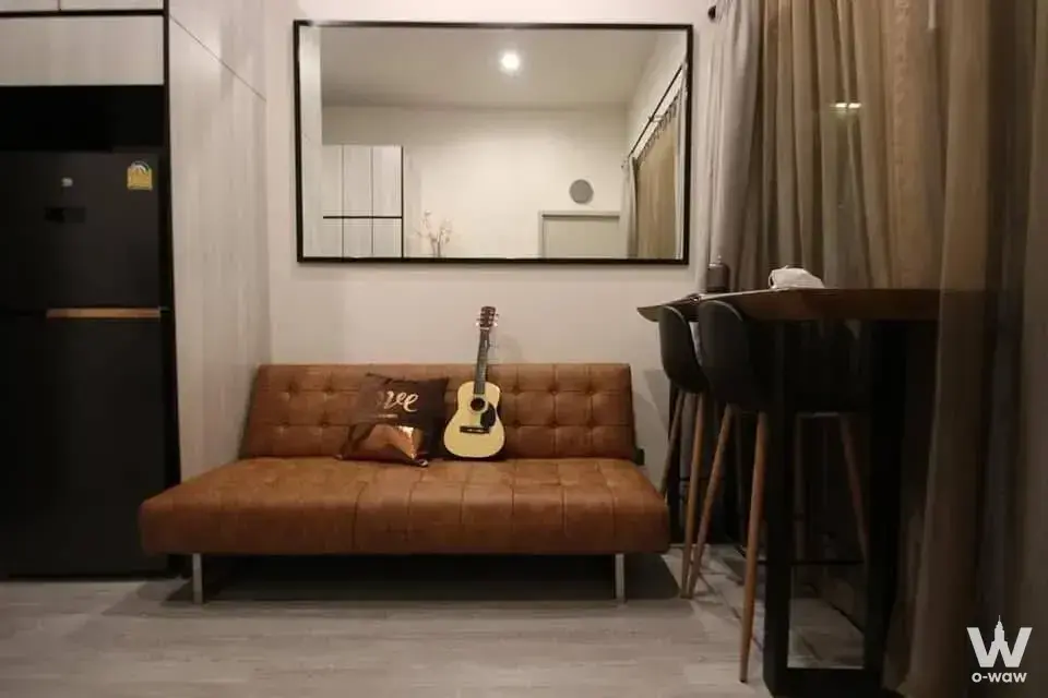 Modern 1-bed THE LINE Sukhumvit 71 living room featuring a brown leather sofa and high-top dining table