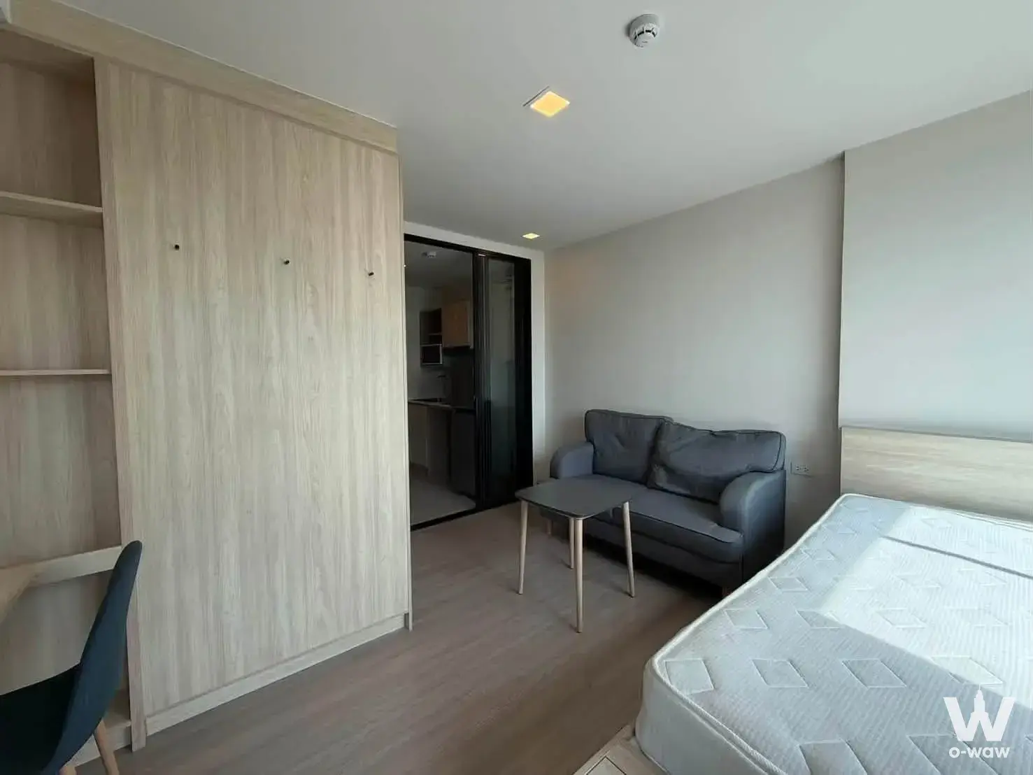 Studio bedroom in THE MUVE Bangkhae includes built-in oak wardrobe and open sliding door to kitchenette