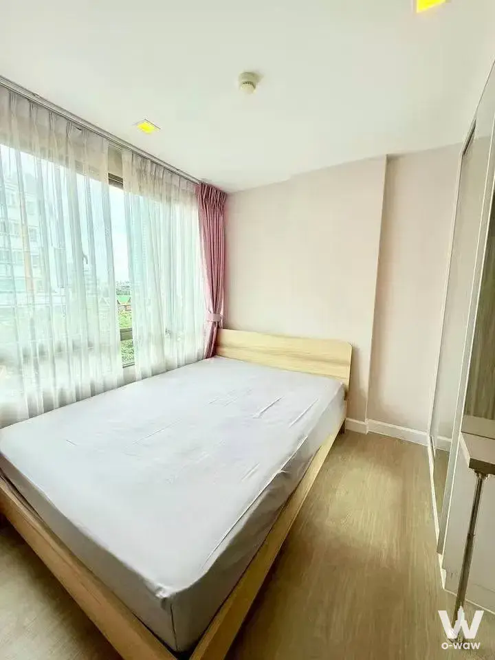 1-bed condo for sale in Metro Luxe Ratchada highlighting a bedroom with city views, sheer curtains, and mirrored built-in