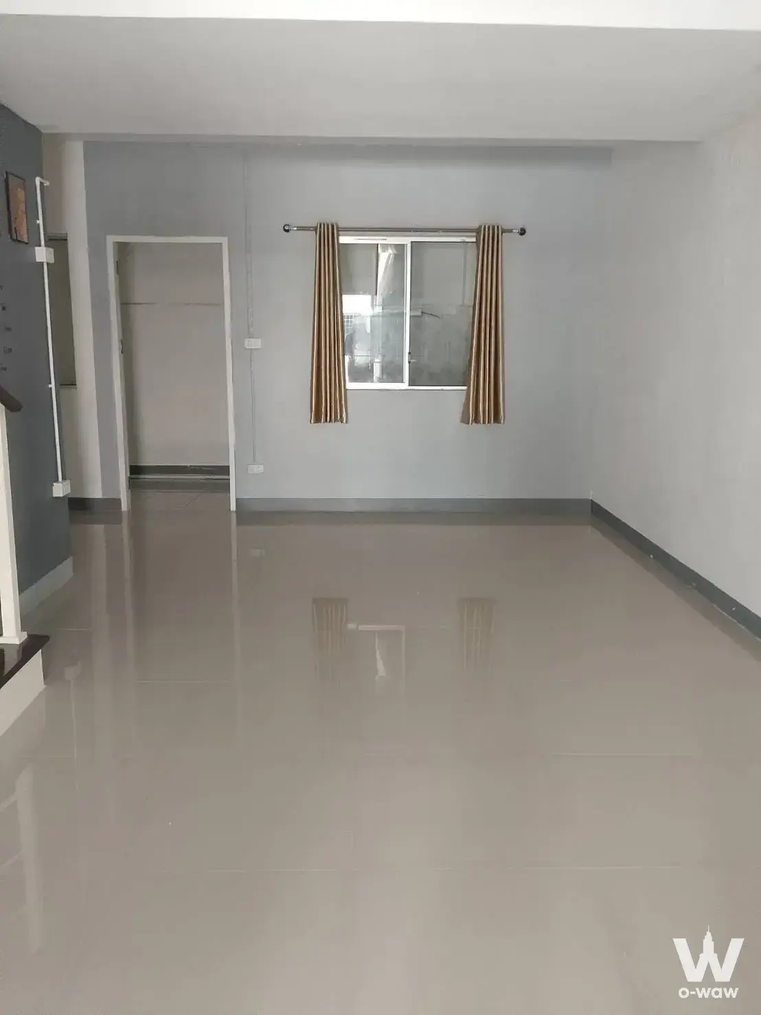 Empty living room in a 3-bed townhouse for sale in หมู่บ้านพฤกษา 70 with high-gloss beige tile floors