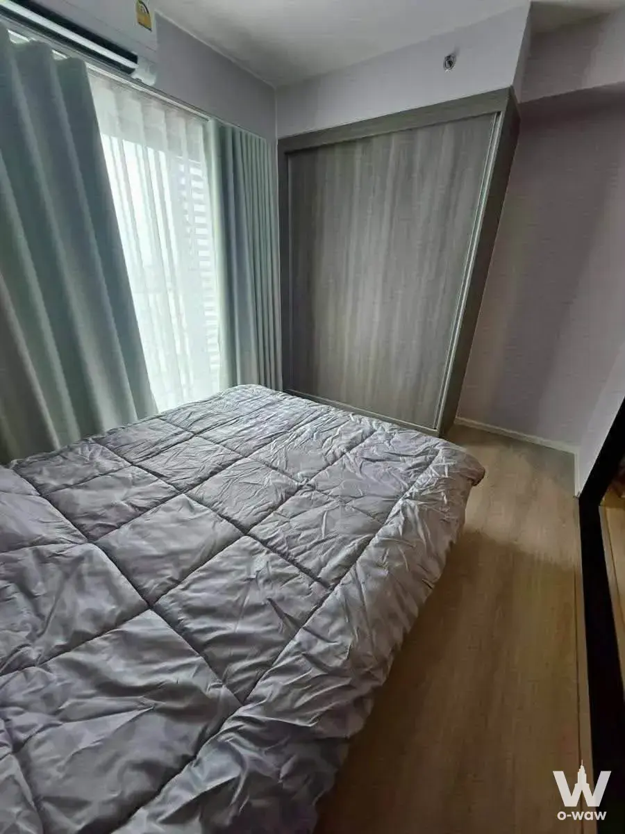 Compact bedroom in an A Space Mega 2 condo with light wood floors and a large window
