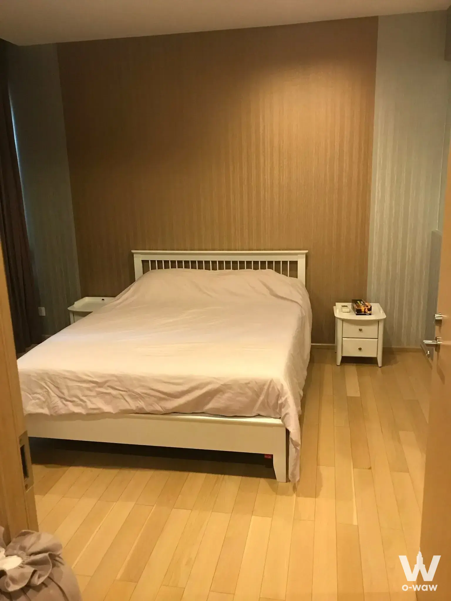 Modern bedroom with white slatted bed frame and textured beige wallpaper in Siri at Sukhumvit condo for rent