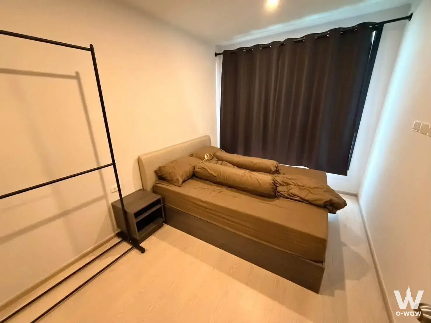 Compact bedroom with single bed, wood nightstand, and blackout curtains in ELIO DEL NEST condo for sale