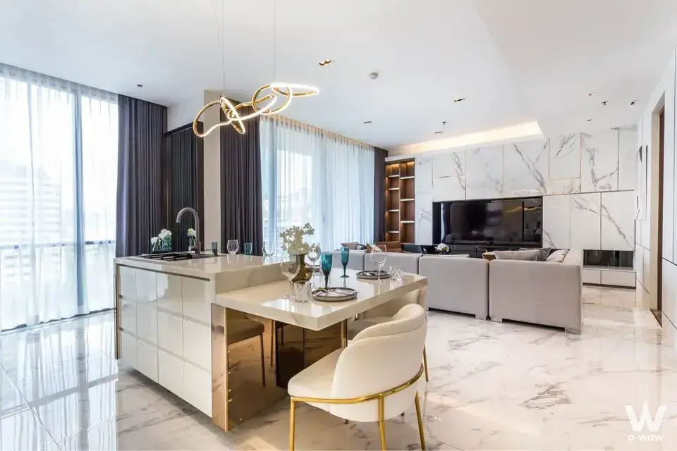 Luxurious open-plan living space featuring white marble floors, gold chandelier, and grey sectional
